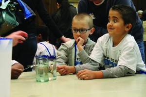 Kindergarteners learn about different sounds made when tapping on glasses filled with water.  Kindergarteners from the Kent school district wisited campus and participated in activities led by PLU students such as this one on Tuesday.  