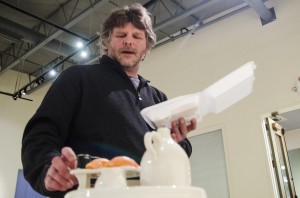 Spencer Ebbinga, associate professor of Art and Design, places sushi on his piece called Sushi/Sake for Two.
